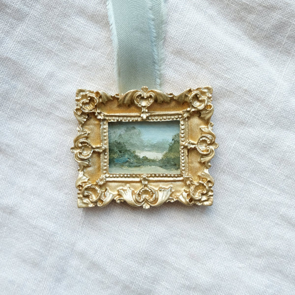 Decorative gold frame with a small painting inside on a light fabric background